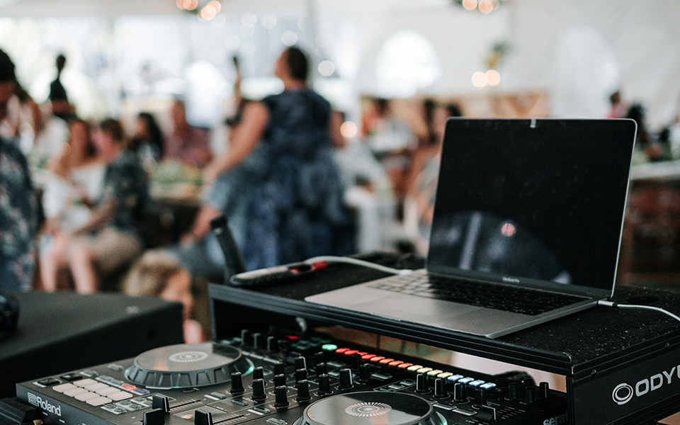 mesa de mistura de DJ, com um casamento ao fundo